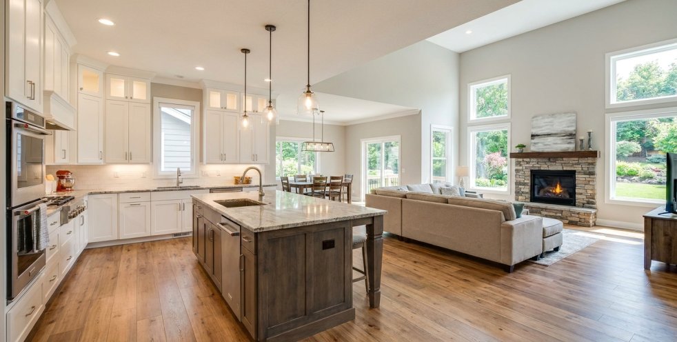 Updated open-concept kitchen and living room with island, fireplace, hardwood floors, and large windows